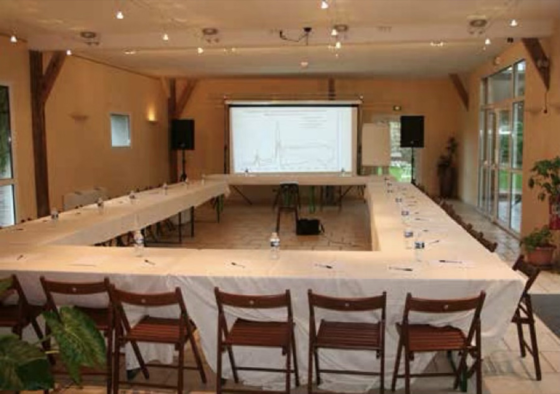 Salle de séminaire de 500 m² sous charpente apparente, aménagée pour un atelier de travail